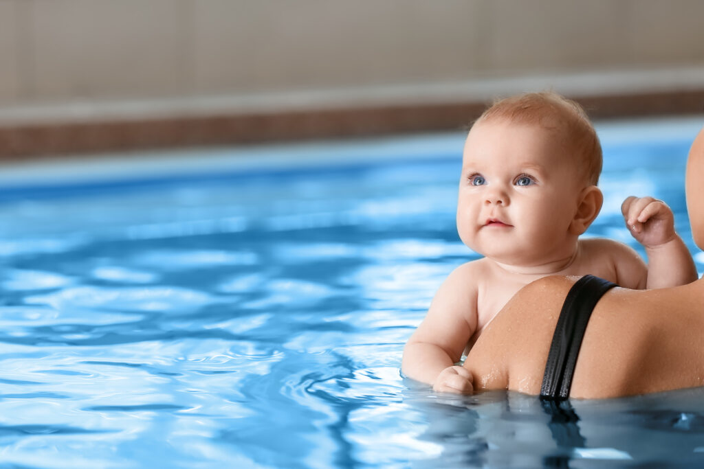 Baby beim Schwimmen mit Elternteil.